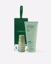 endota 'Signature Care' gift set featuring a light green hand therapy tube, a small green essential oil bottle, and a dark green bon bon gift box with a carrying loop, on a light grey background.