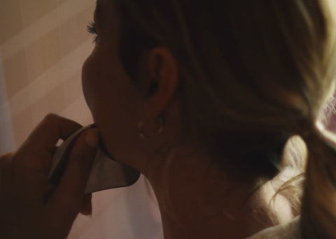 Person using a facial gua sha on their jawbone.