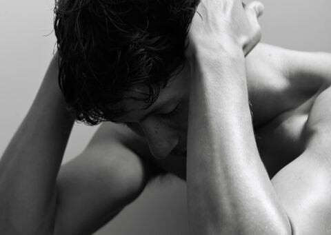 Black and white photo of a person with their head in their hands in distress.