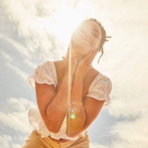 woman smiling with sun shining through clouds